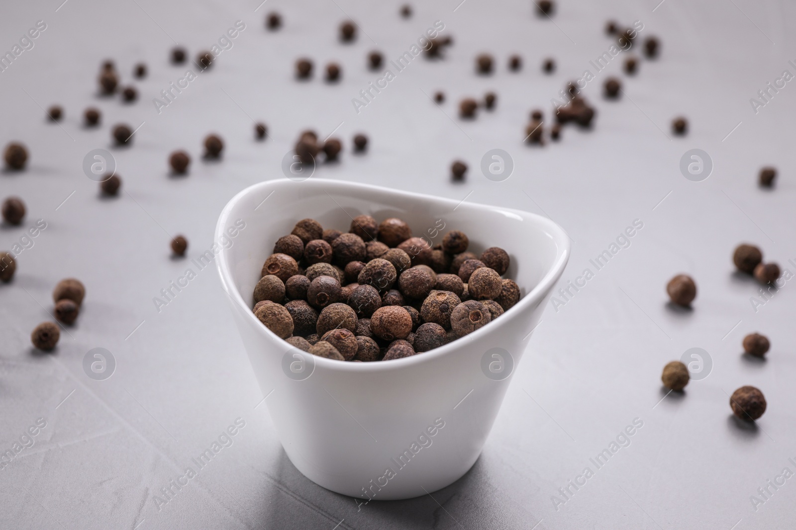 Photo of Black peppercorns in bowl on grey table