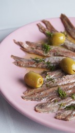 Canned anchovy fillets with olives on white table