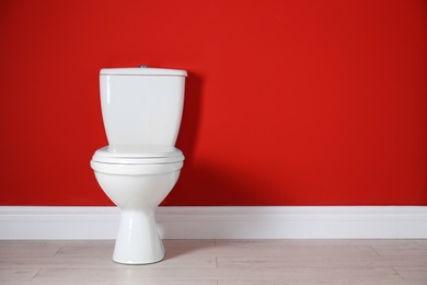 Photo of Toilet bowl near color wall in restroom. Space for text