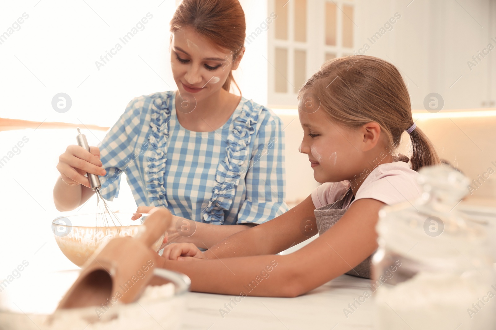 Photo of Mother and daughter making dough together in kitchen