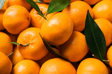 Photo of Fresh ripe tangerines with leaves as background, above view. Citrus fruit