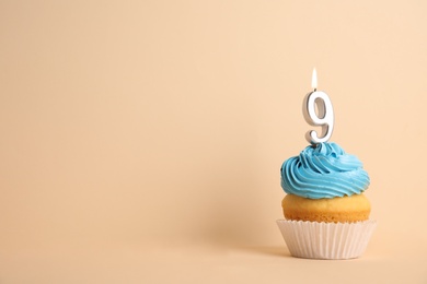 Photo of Birthday cupcake with number nine candle on beige background, space for text