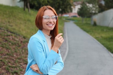 Portrait of beautiful woman in glasses outdoors, space for text