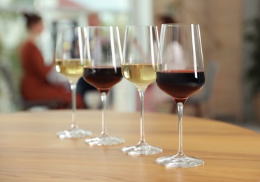 Glasses with different wines on table against blurred background