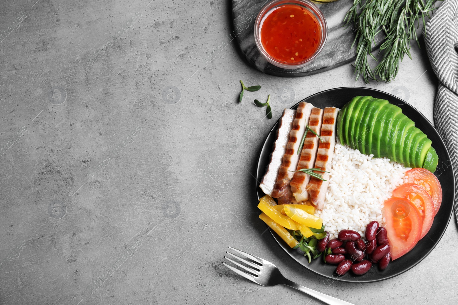 Photo of Delicious rice with beans and meat served on grey table, flat lay. Space for text