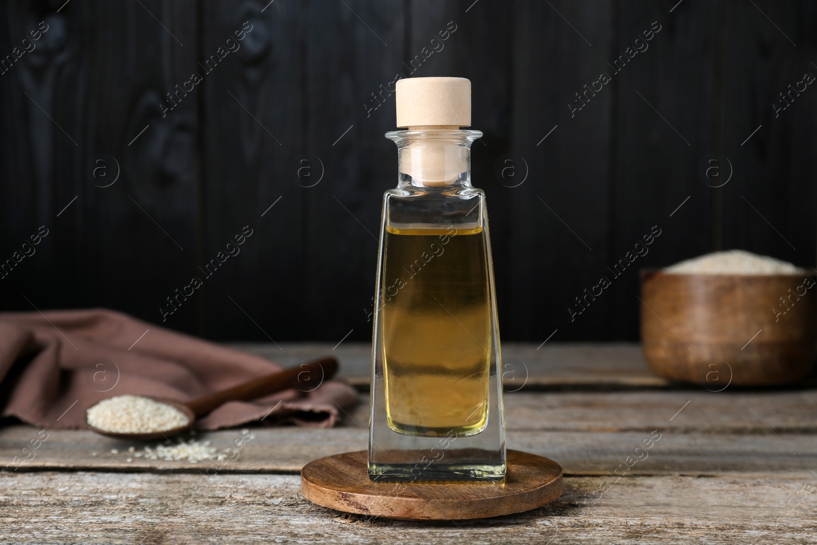 Photo of Bottle of organic sesame oil on wooden table