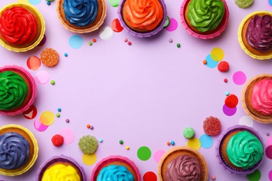 Photo of Frame of delicious colorful cupcakes and confetti on violet background, flat lay. Space for text
