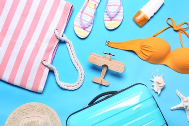 Photo of Flat lay composition with suitcase and beach objects on blue background