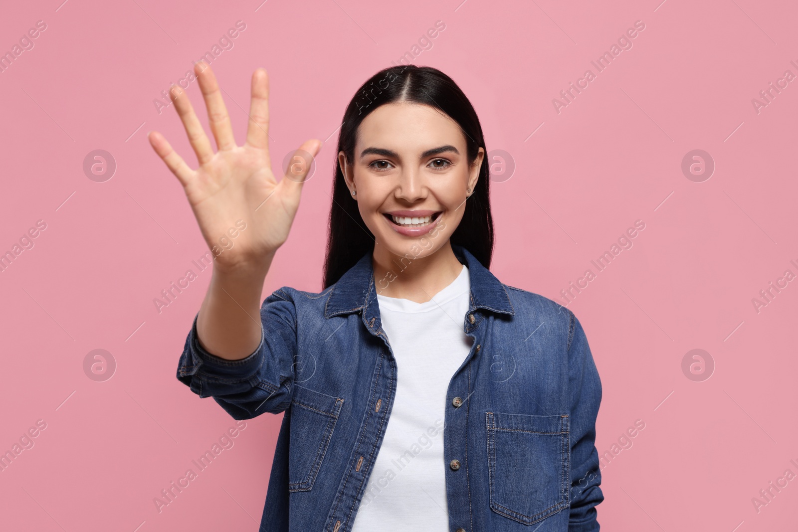 Photo of Happy woman giving high five on pink background