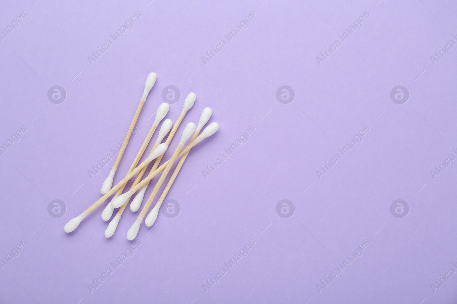 Photo of Wooden cotton buds on violet background, flat lay. Space for text