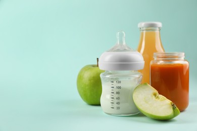 Photo of Healthy baby food, apple, milk and juice on light blue background, space for text