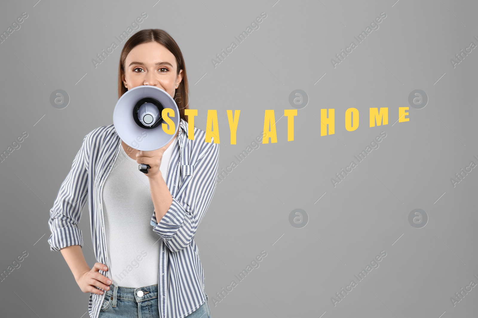 Image of Young woman with megaphone on grey background. Stay at home during coronavirus outbreak 