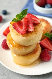 Delicious cottage cheese pancakes with fresh berries, mint and honey on light table, closeup