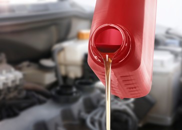 Image of Pouring motor oil from red container, closeup