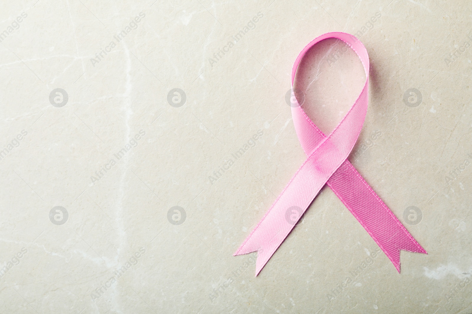 Photo of Pink ribbon on grey background, top view with space for text. Breast cancer awareness concept