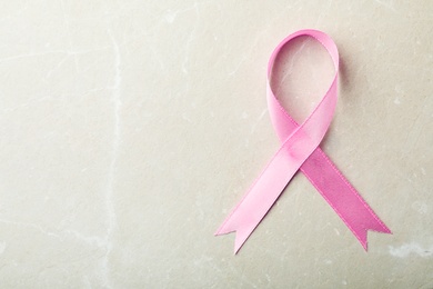 Photo of Pink ribbon on grey background, top view with space for text. Breast cancer awareness concept