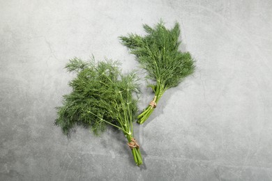 Photo of Bunches of fresh dill on light grey table, flat lay