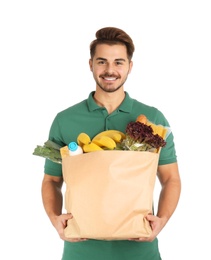 Young man holding paper bag with products on white background. Food delivery service