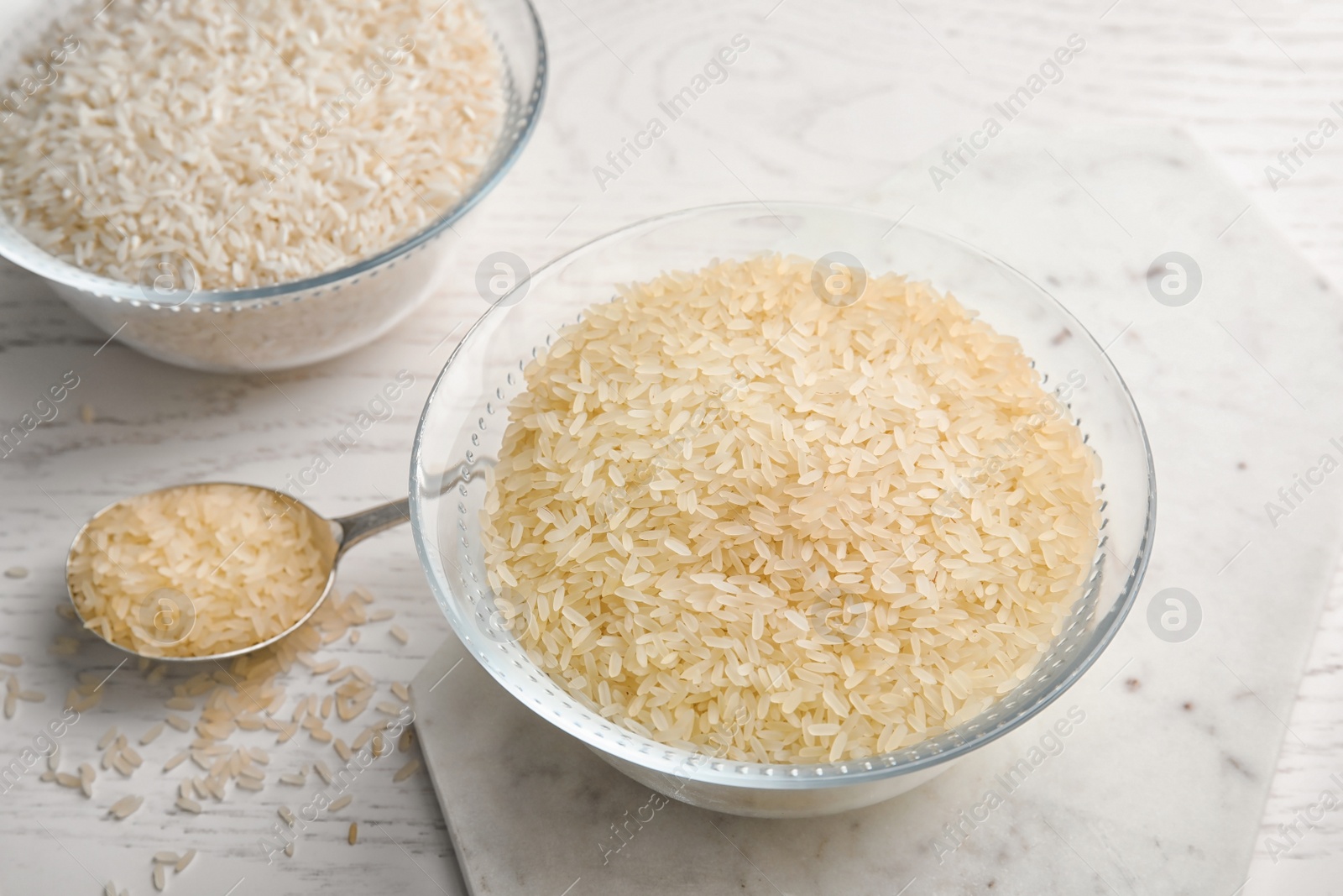 Photo of Bowls and spoon with different types of rice on wooden table