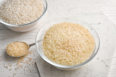 Bowls and spoon with different types of rice on wooden table