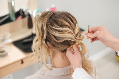 Hair styling. Professional hairdresser working with client indoors, closeup