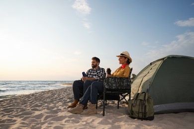 Photo of Couple with thermoses near camping tent on beach
