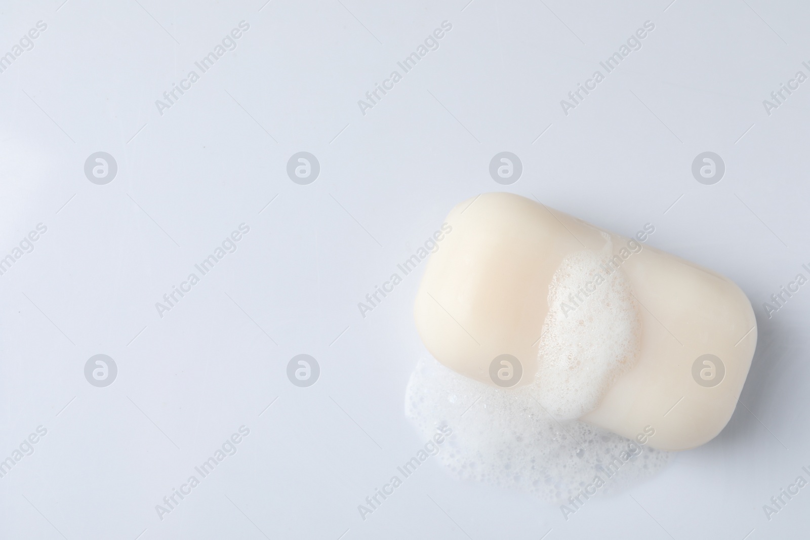 Photo of Soap with fluffy foam on white background, top view. Space for text