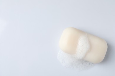 Soap with fluffy foam on white background, top view. Space for text