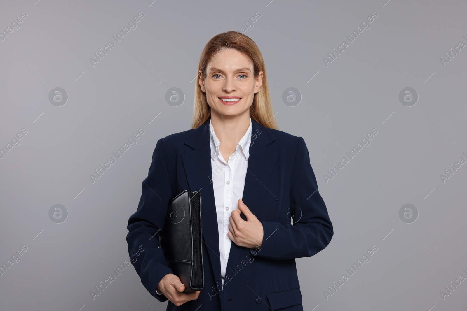 Photo of Happy real estate agent with leather portfolio on grey background