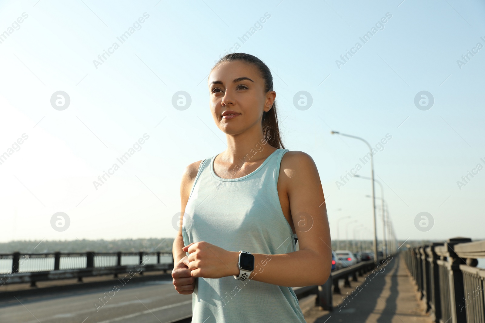 Photo of Woman wearing modern smart watch during training outdoors
