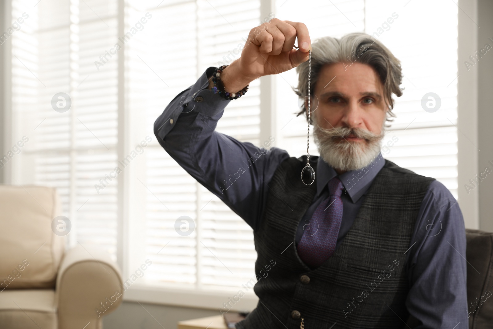 Photo of Psychotherapist with pendulum in office, space for text. Hypnotherapy session