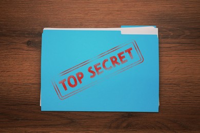 Image of Light blue file with documents and Top Secret stamp on wooden table, top view