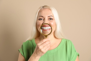 Photo of Smiling woman with perfect teeth and magnifier on color background