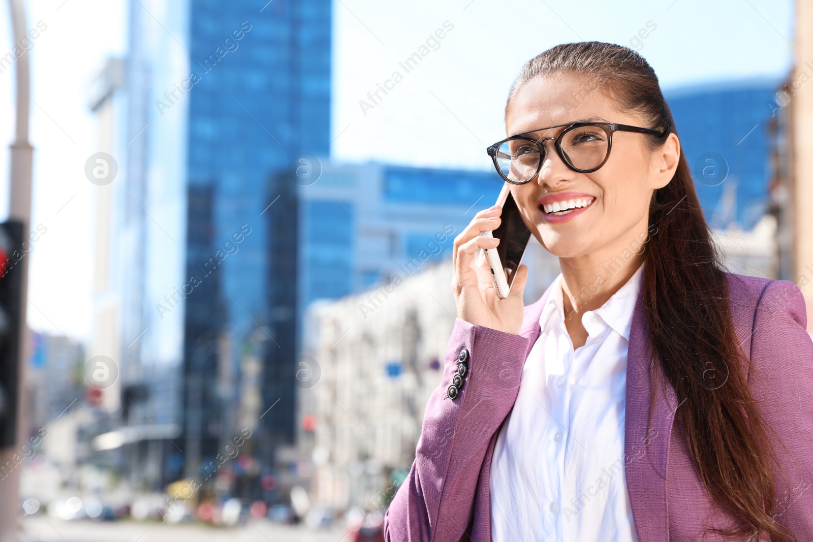 Photo of Beautiful businesswoman talking on phone in city on sunny day