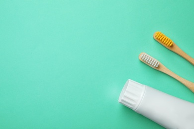 Photo of Blank tube of toothpaste and brushes on color background, top view with space for text