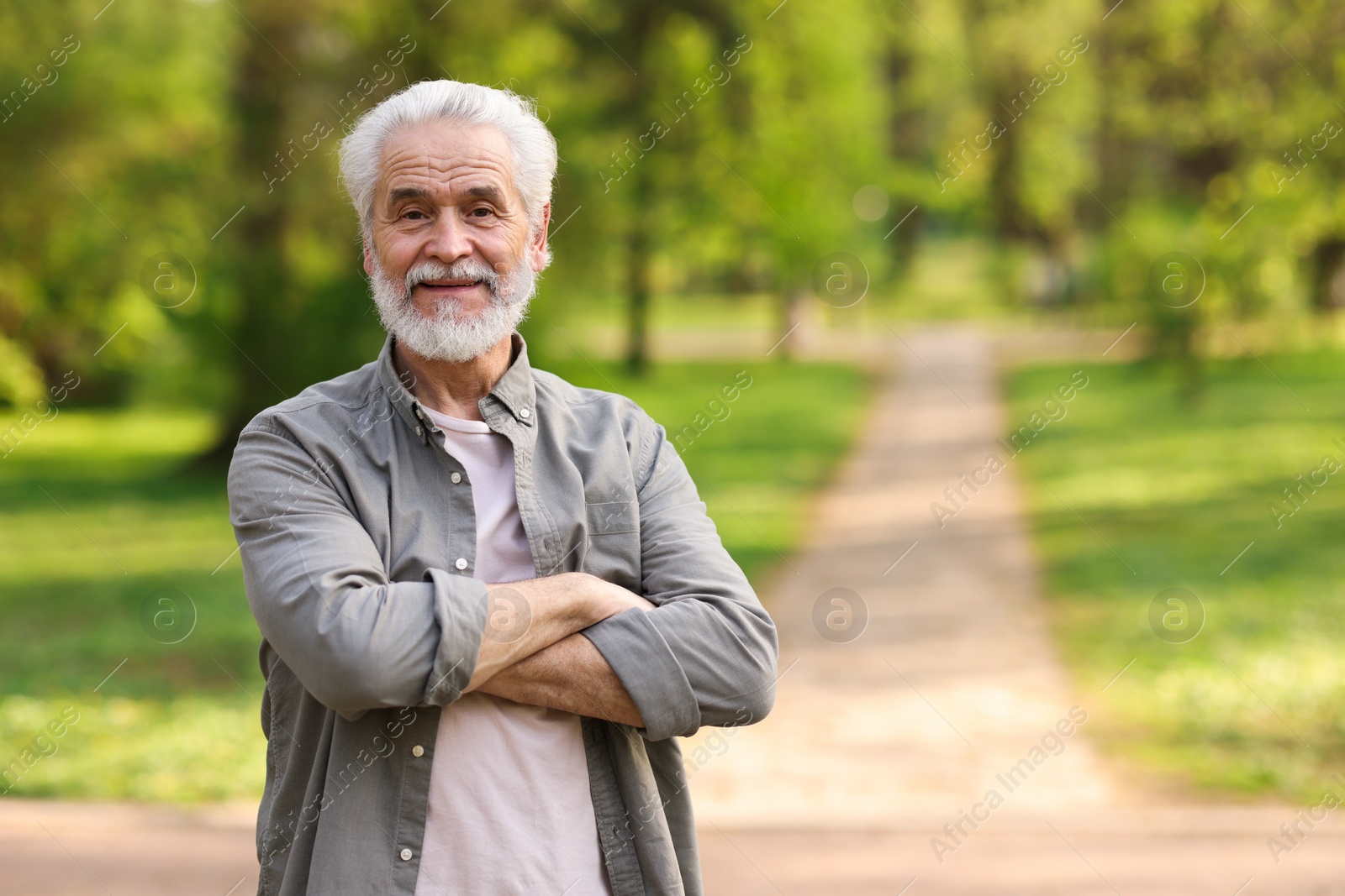 Photo of Portrait of happy grandpa with grey hair in park, space for text