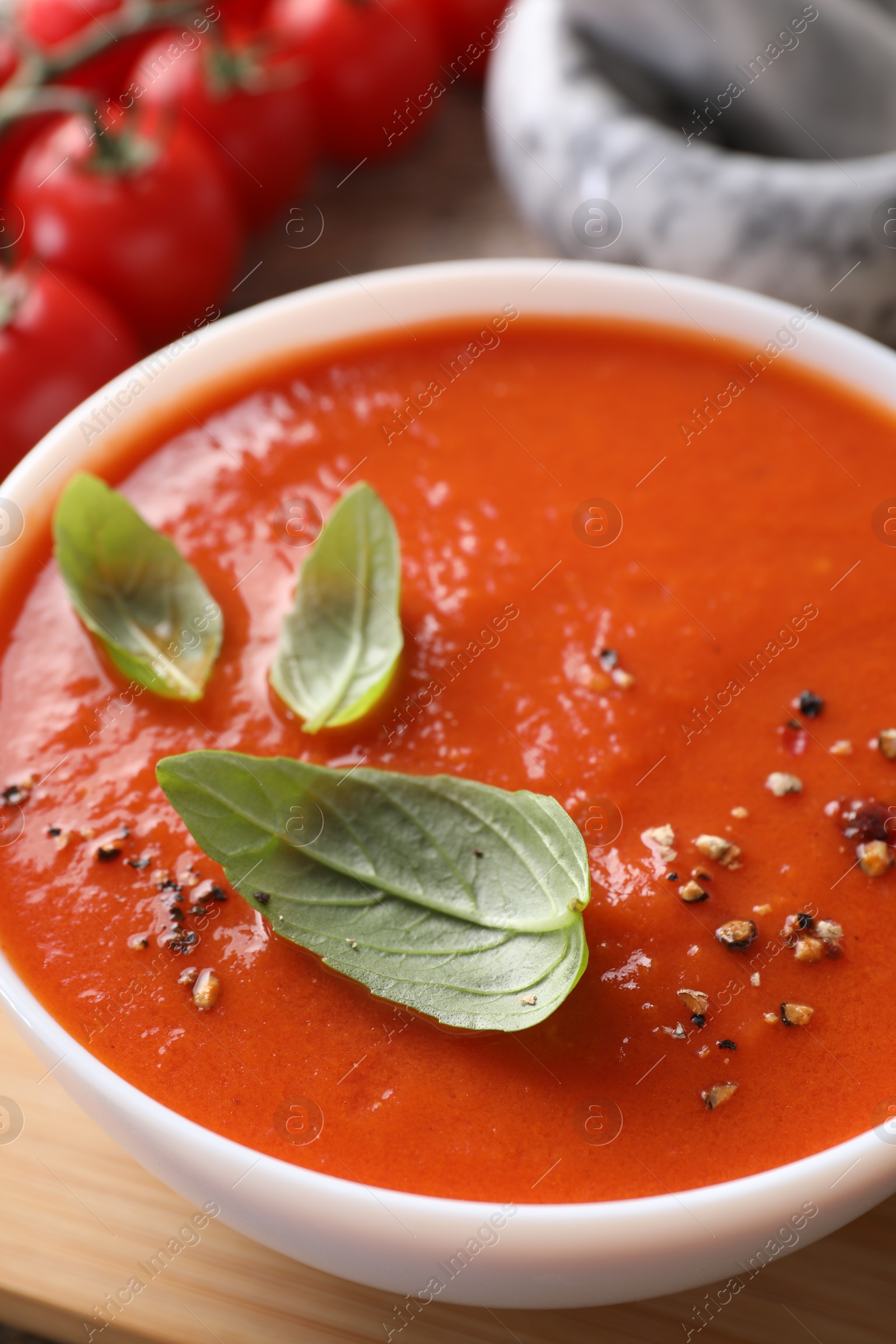 Photo of Delicious tomato soup with basil and spices on table, closeup