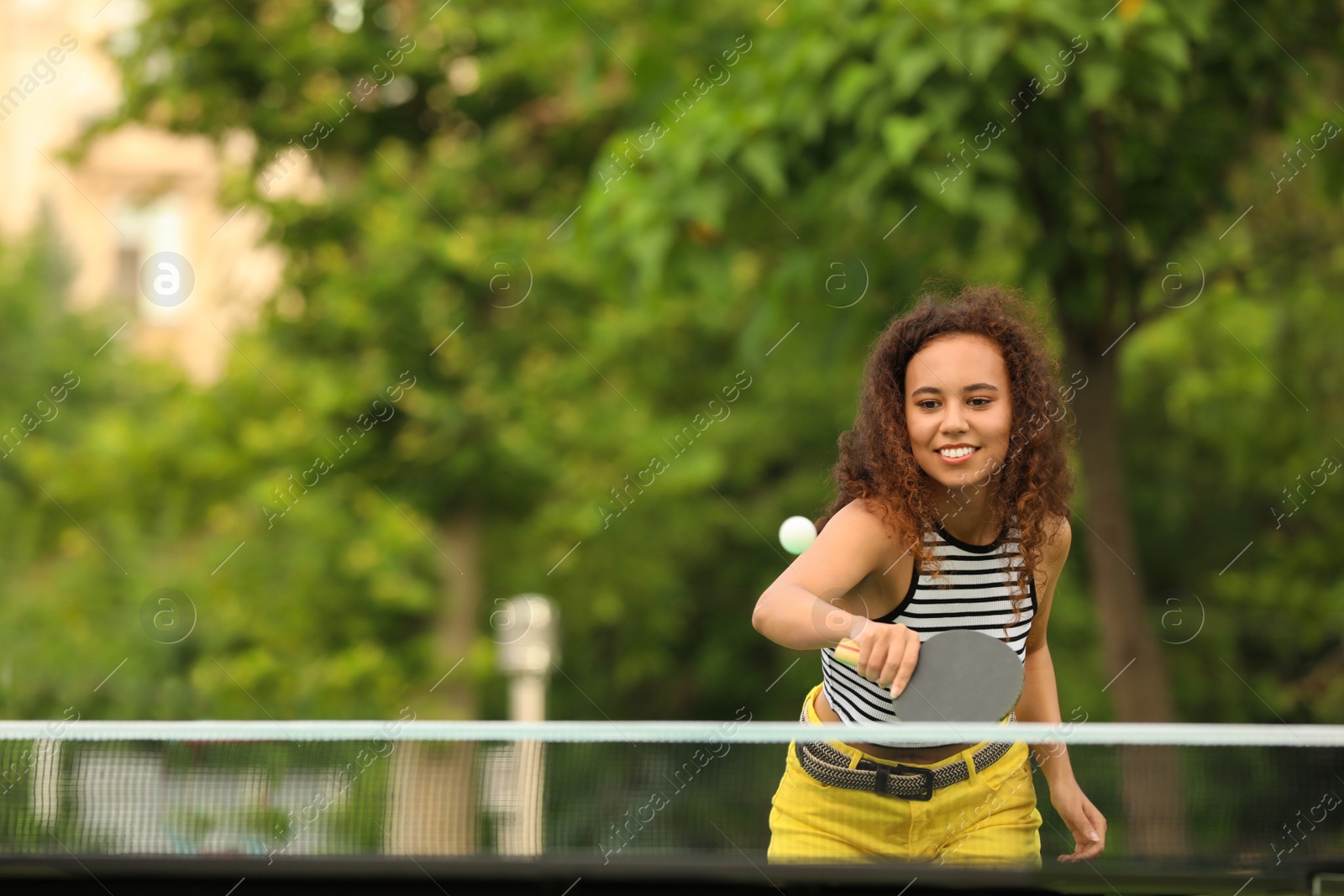 Photo of Young African-American woman playing ping pong outdoors