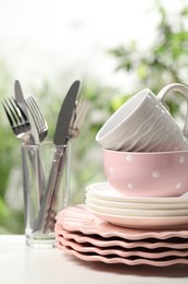 Photo of Beautiful ceramic dishware, cutlery and cup on white table outdoors