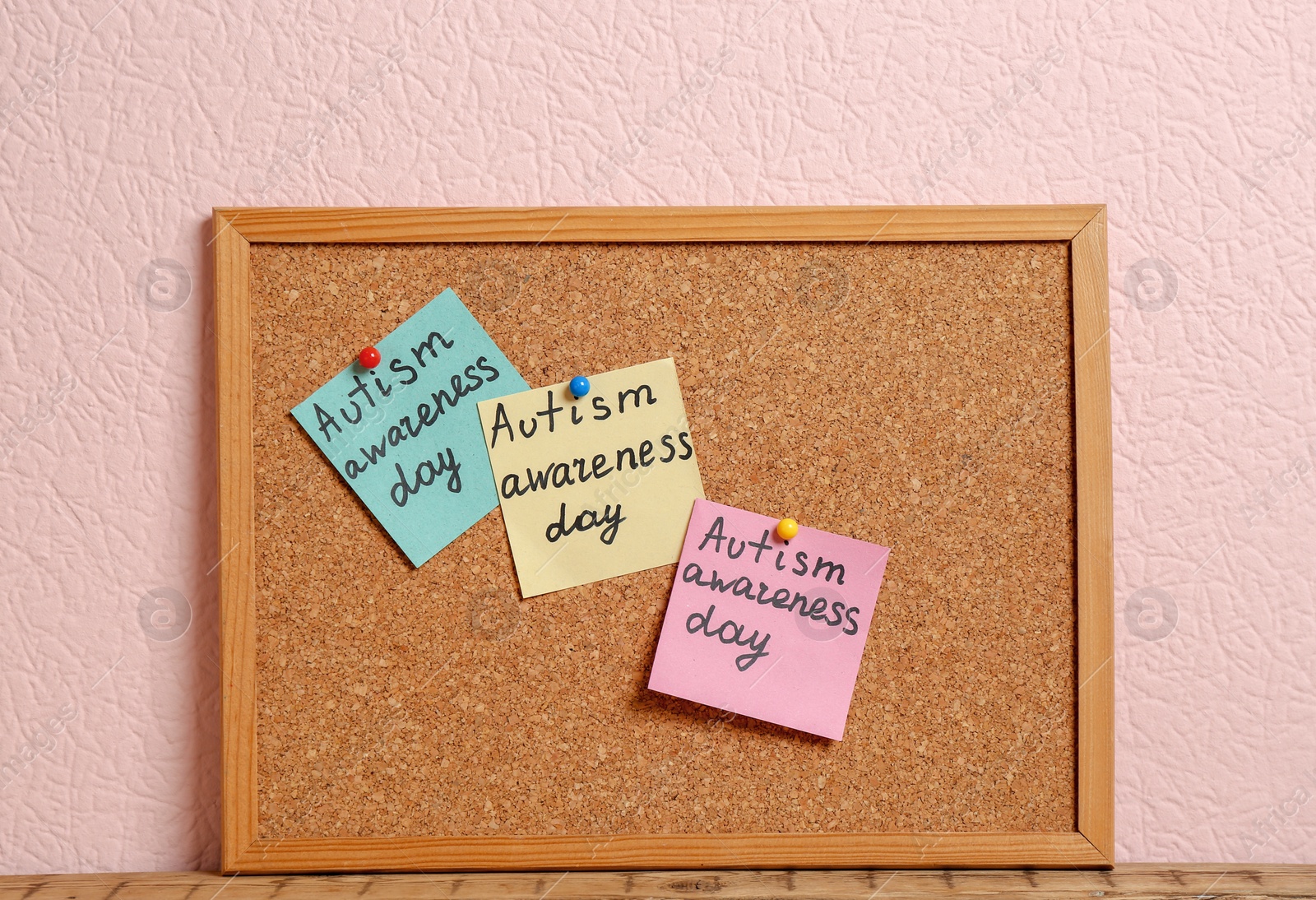 Photo of Notes with phrase "Autism awareness day" on cork board against color background