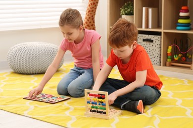 Photo of Children playing with math game kits on floor in room. Learning mathematics with fun