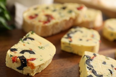 Photo of Tasty butter with olives, chili pepper and parsley on wooden table, closeup