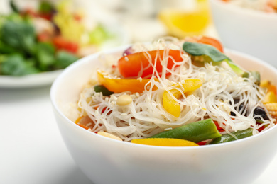 Tasty cooked rice noodles with vegetables on table, closeup