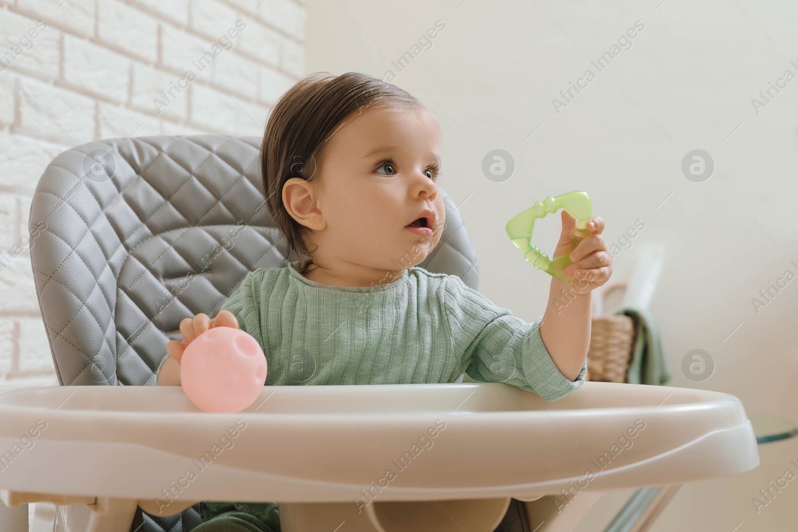 Photo of Cute little baby with teether and toy in high chair indoors