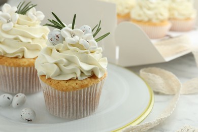 Photo of Tasty Easter cupcakes with vanilla cream on table, closeup