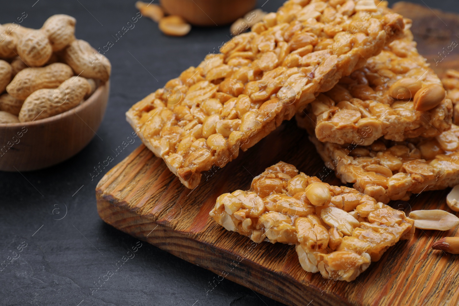 Photo of Delicious peanut bars (kozinaki) and ingredients on black table, closeup