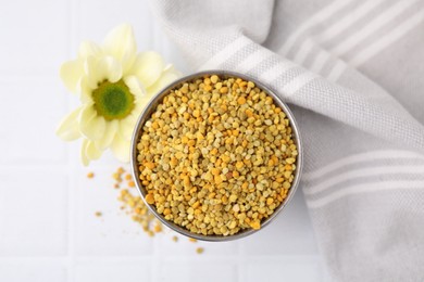 Photo of Fresh bee pollen granules and flower on white table, top view