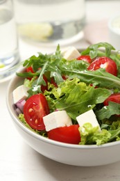 Photo of Delicious salad with arugula and vegetables on white table, closeup