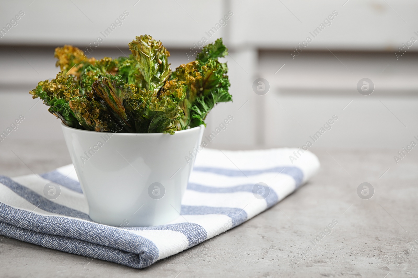 Photo of Tasty baked kale chips on grey table. Space for text