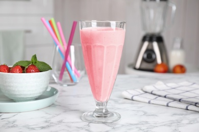 Photo of Tasty milk shake and strawberries on white marble table